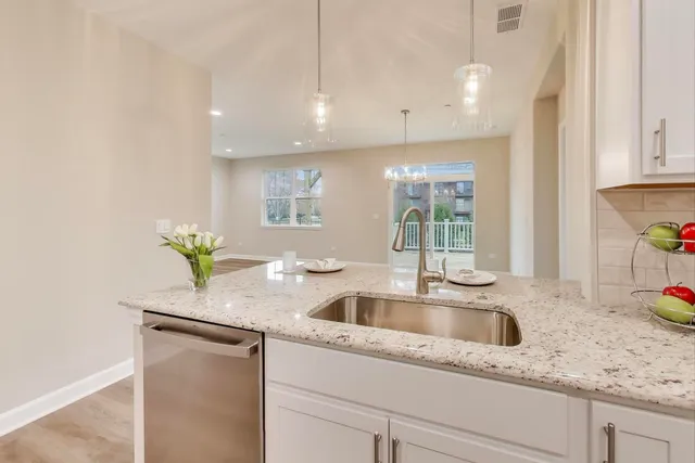 a kitchen with granite countertop a sink and a white wooden cabinets
