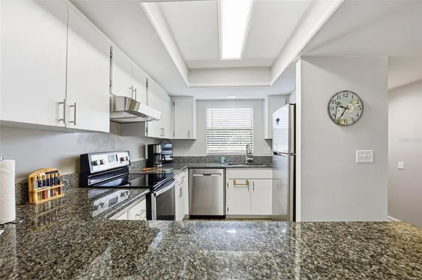 a kitchen with stainless steel appliances granite countertop a sink stove refrigerator and cabinets