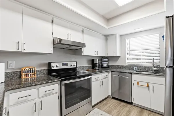 a kitchen with white cabinets and appliances