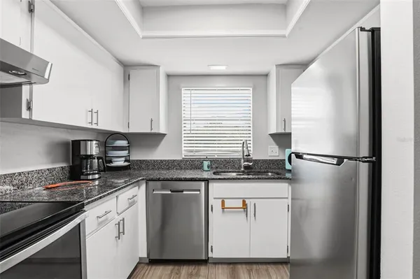 a kitchen with granite countertop cabinets stainless steel appliances and a sink