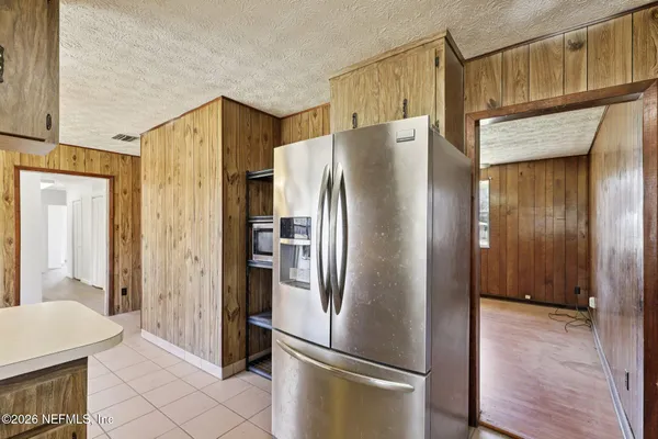 an empty room with wooden floor chandelier fan and windows