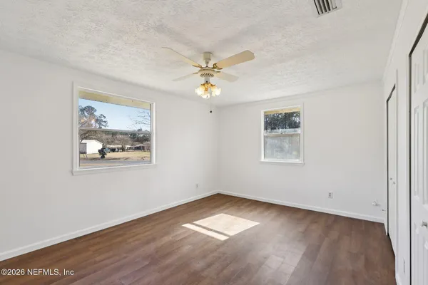 a view of an empty room with a window and wooden floor