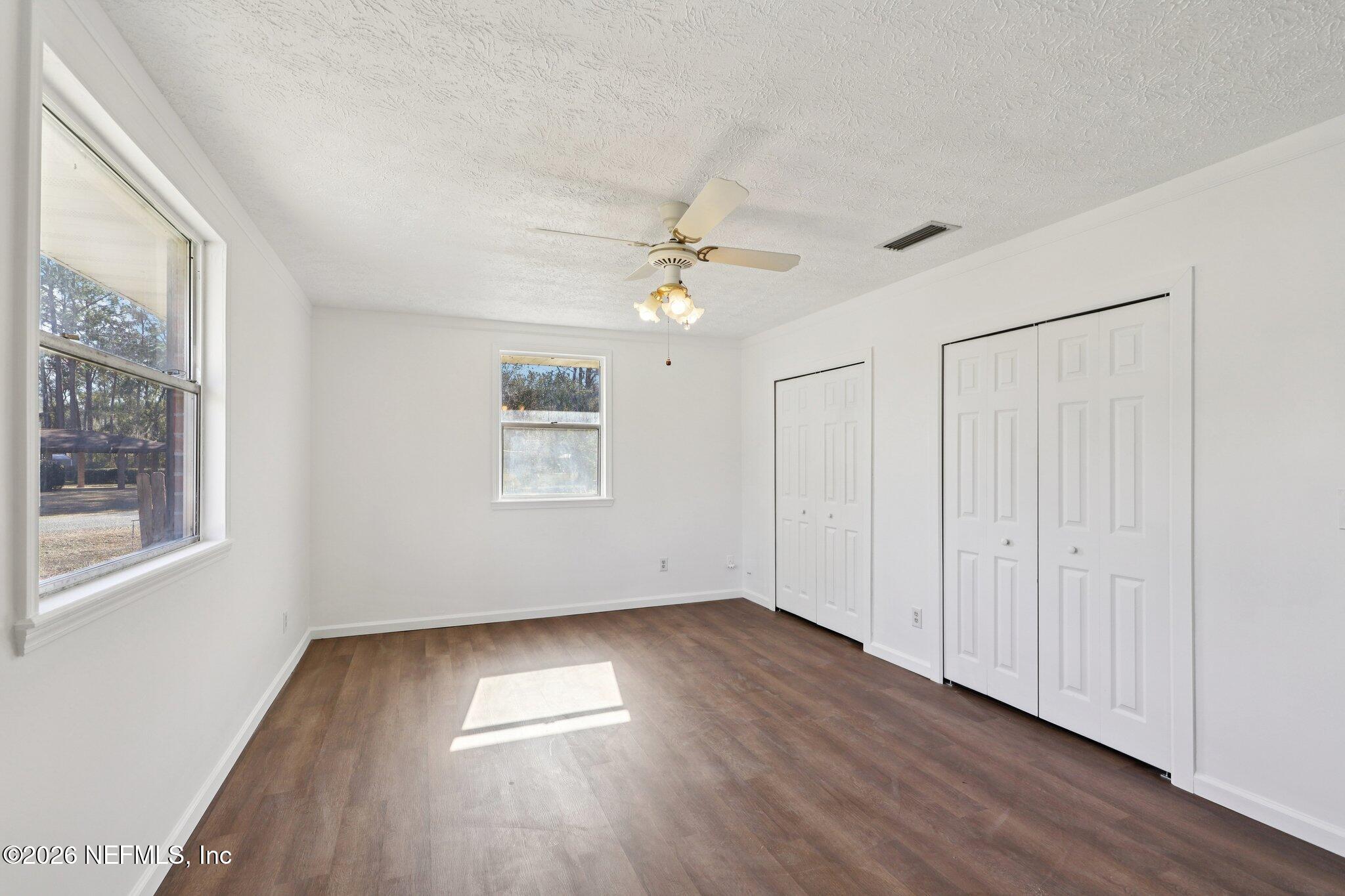 54031 Sheffield Road Callahan, FL 32011 - Photo 20 of 56 an empty room with wooden floor chandelier fan and windows