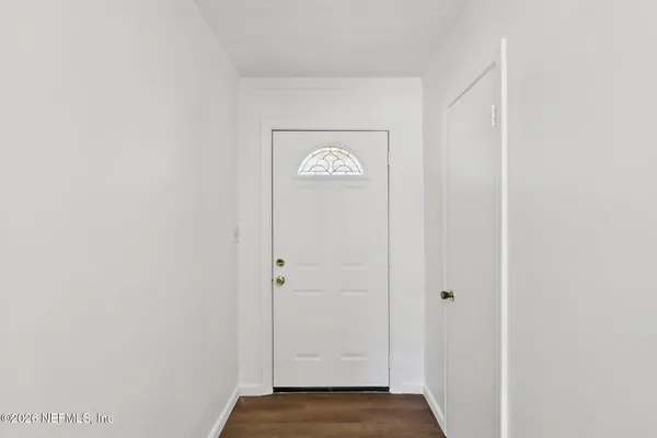 a view of an empty room with a window and wooden floor