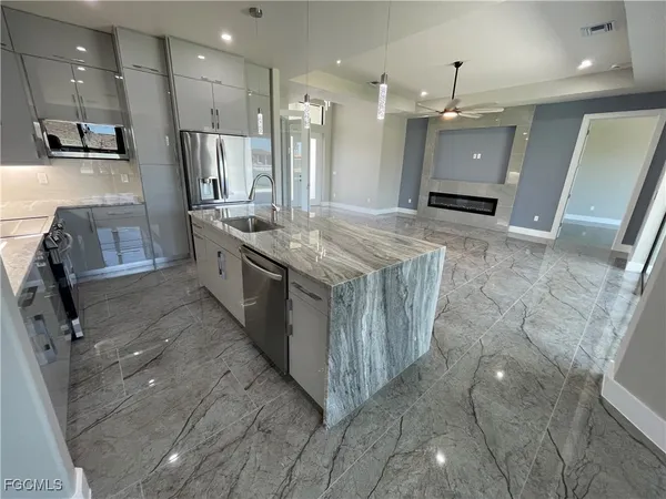 a large kitchen with stainless steel appliances kitchen island granite countertop a large counter top a stove a sink and a refrigerator