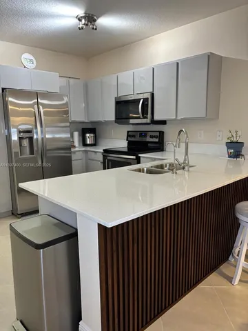 a kitchen with stainless steel appliances a sink a stove a refrigerator and cabinets