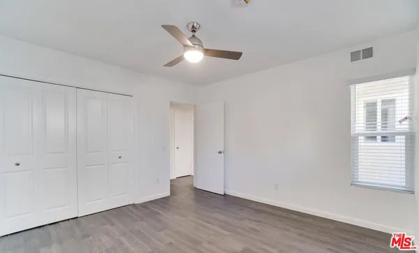 an empty room with wooden floor ceiling fan and windows