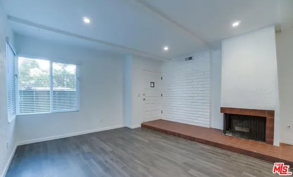 an empty room with wooden floor a fireplace and windows