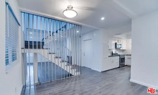 a view of a kitchen with a refrigerator and wooden floor