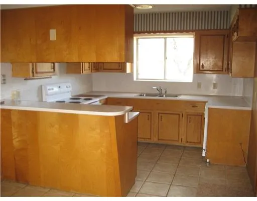 a kitchen with stainless steel appliances granite countertop a sink a stove a chimney a refrigerator and cabinets