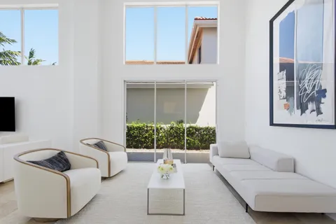 a living room with furniture a flat screen tv and a floor to ceiling window
