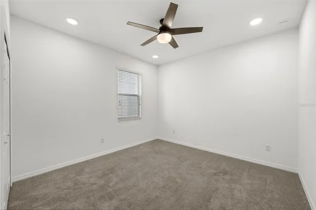 an empty room with a ceiling fan and window