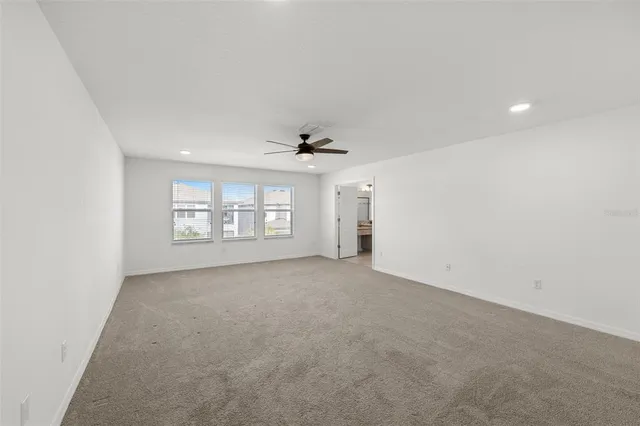 an empty room with windows and ceiling fan