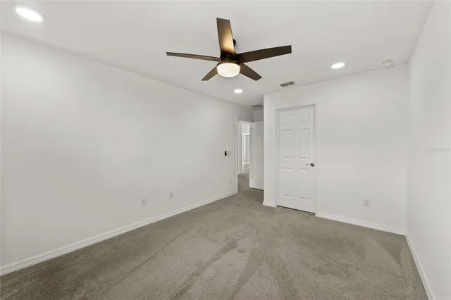 an empty room with a ceiling fan and a window