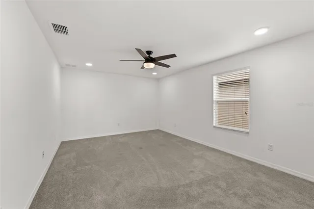 an empty room with a ceiling fan and window