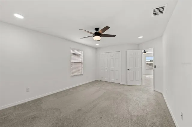 an empty room with closet and a ceiling fan