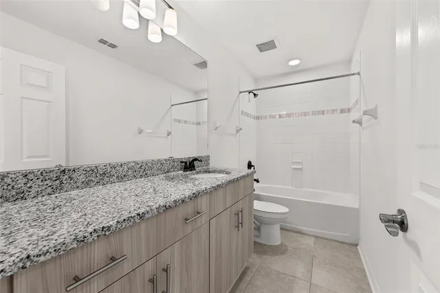 a bathroom with a granite countertop sink a toilet a mirror and shower