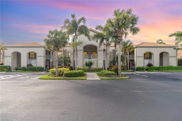 a view of a white house with a small yard and palm trees