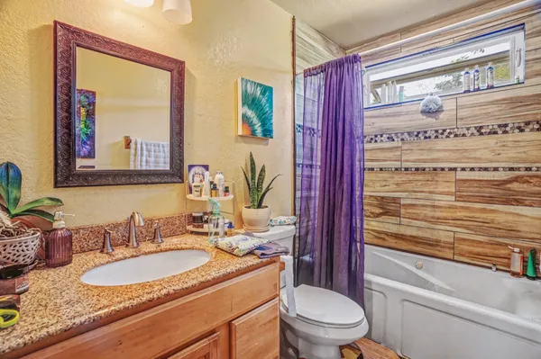 a bathroom with a granite countertop toilet a sink and a mirror