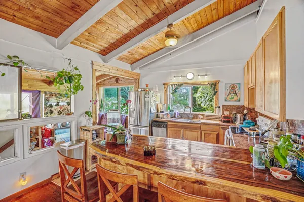 a kitchen with a stove a refrigerator and a dining table with wooden floor