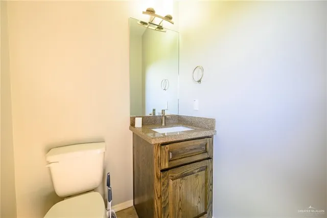 a bathroom with a granite countertop toilet sink and mirror