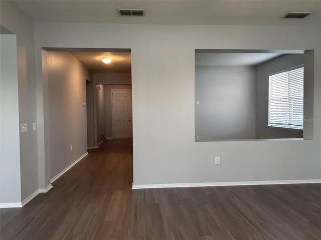 a view of an empty room with wooden floor and windows