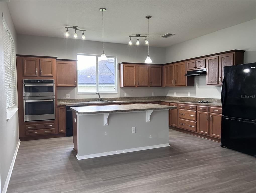 4432 Barbados Loop Clermont, FL 34711 - Photo 5 of 19 a kitchen with kitchen island granite countertop a stove cabinets and refrigerator