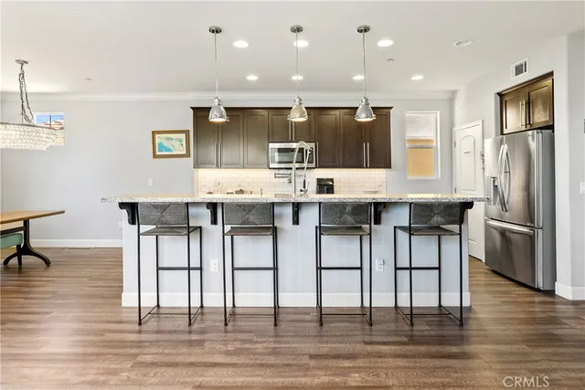 a kitchen with kitchen island granite countertop a table chairs refrigerator and microwave