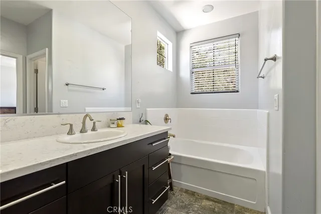 a bathroom with a double vanity sink a mirror and a bathtub