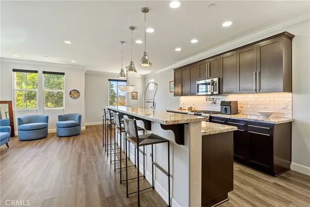 a kitchen with stainless steel appliances granite countertop a stove top oven a sink dishwasher a dining table and chairs with wooden floor