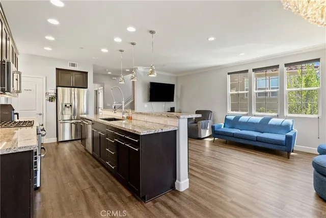 a kitchen with stainless steel appliances granite countertop wooden cabinets a sink dishwasher a stove and a refrigerator