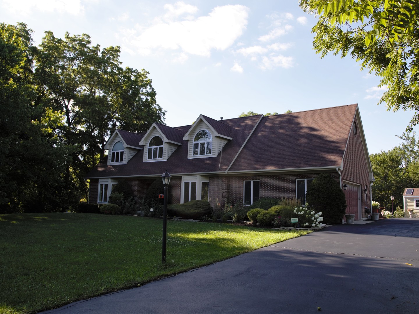a view of a white house with a big yard and large trees