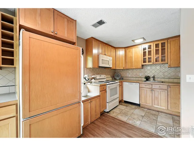 a kitchen with granite countertop a refrigerator a sink and white cabinets