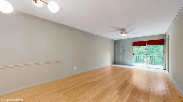 a view of an empty room with a window and wooden floor