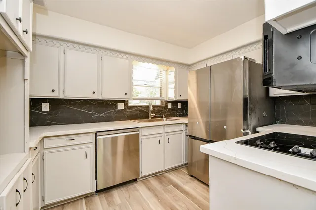 a kitchen with white cabinets and appliances