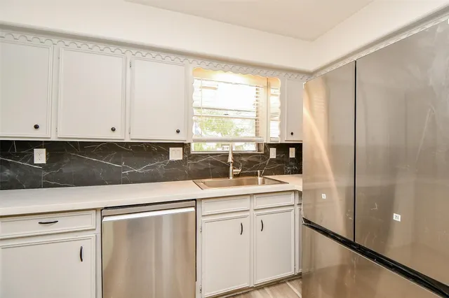 a kitchen with stainless steel appliances granite countertop white cabinets and window