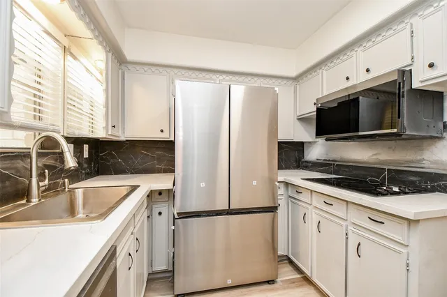 a kitchen with a refrigerator stove and sink with wooden cabinets