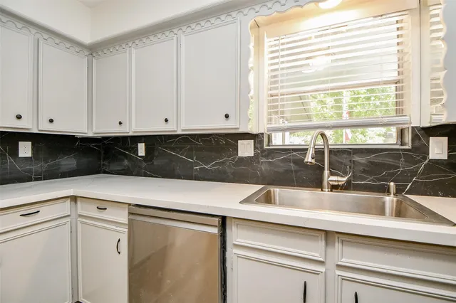 a kitchen with granite countertop white cabinets and sink