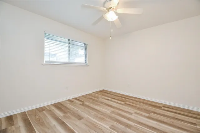 an empty room with a window and ceiling fan