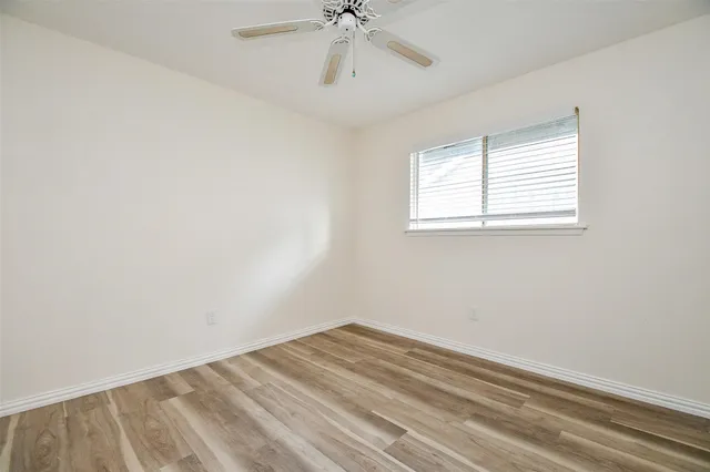 an empty room with a window and a ceiling fan