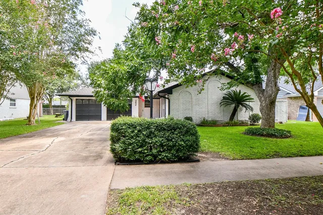 a front view of a house with a garden and trees