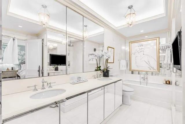 a spacious bedroom with a bed a couch and a flat tv screen on dresser