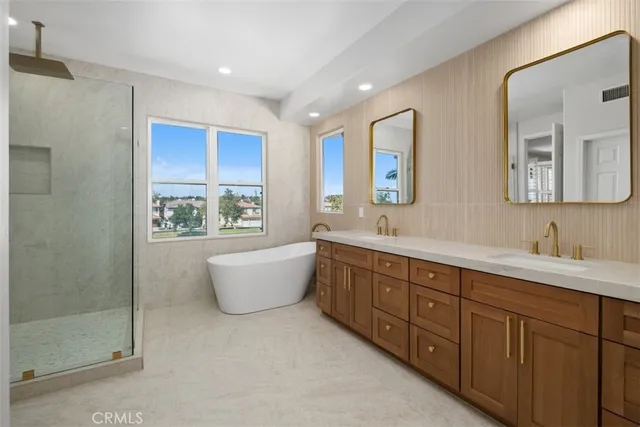 a spacious bathroom with double vanity sink a large mirror a bathtub and window