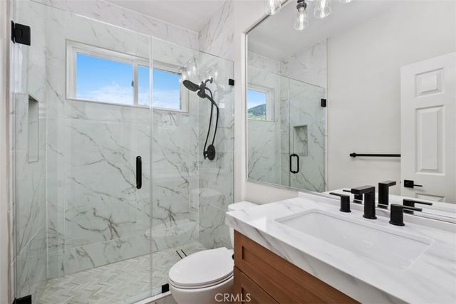 a bathroom with a granite countertop sink a toilet and shower