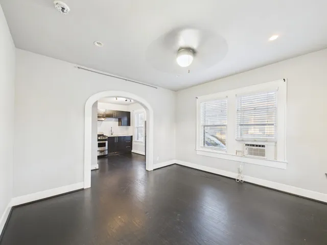an empty room with wooden floor and a large window