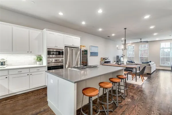 a kitchen with stainless steel appliances granite countertop a table chairs sink refrigerator and microwave