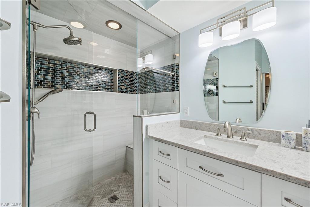 900 Hidden Harbour Drive Naples, FL 34109 - Photo 17 of 32 a bathroom with a granite countertop sink a mirror and shower