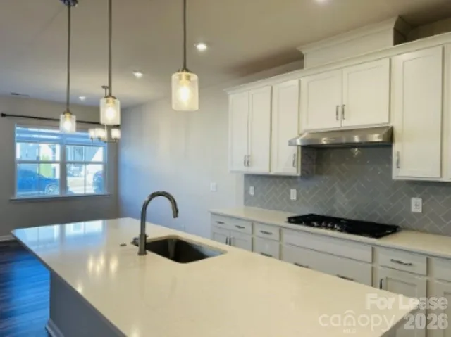 a kitchen with granite countertop a sink a stove and cabinets