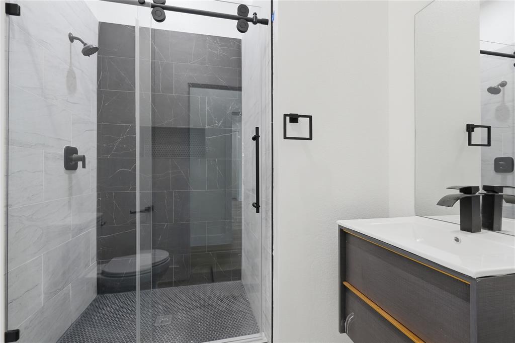 3905 Blue Ridge Boulevard Dallas, TX 75233 - Photo 10 of 25 Glass-enclosed shower with matte black fixtures and a sliding barn door