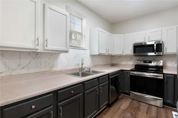 a kitchen with stainless steel appliances granite countertop a sink dishwasher a stove and a microwave oven with white cabinets
